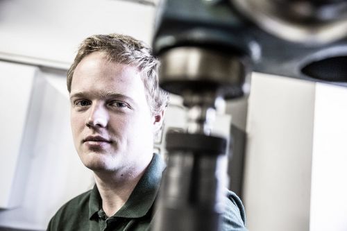 Ein Mann arbeitet konzentriert an Geräten für Klimatechnik in einem technischen Raum in München.