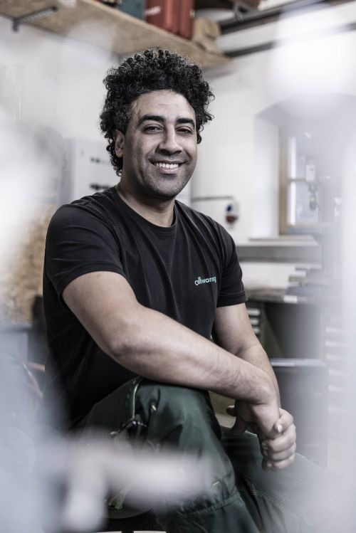 Ein lächelnder Mann sitzt entspannt in einer Werkstattumgebung, ideal für Heiztechnik oder Klimatechnik.