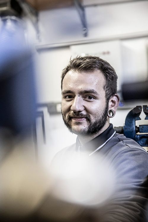 Ein lächelnder Experte für Heiztechnik arbeitet konzentriert in seiner Werkstatt an einem Projekt.