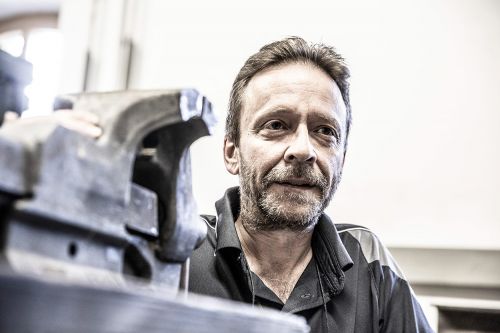 Ein Mann arbeitet konzentriert an einem Projekt in einer Heiztechnik-Werkstatt, umgeben von Werkzeugen und Geräten.