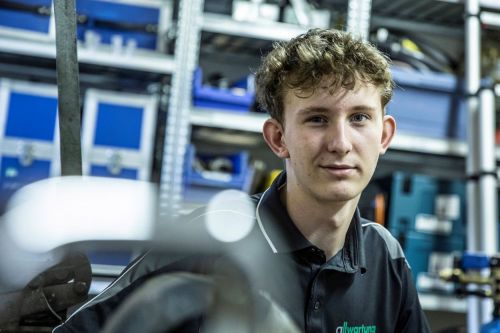 Ein junger Azubi in einem Technikraum in München lernt begeistert über moderne Klimatechnik.