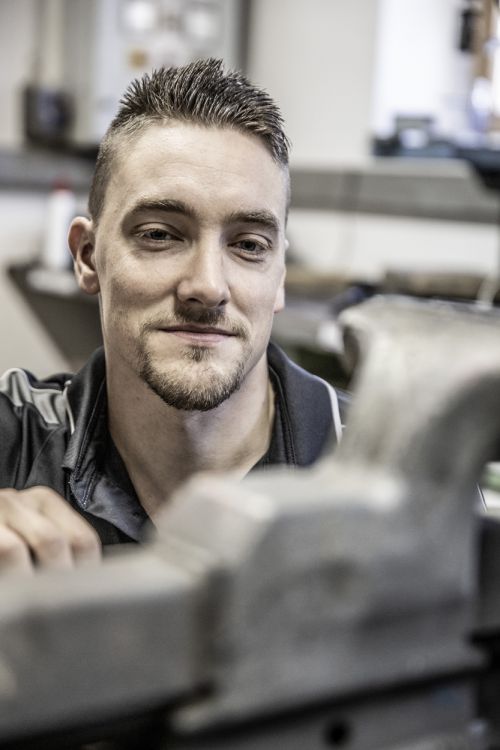 Ein Mann konzentriert sich in der Werkstatt auf präzise Arbeiten an einem Stück, das zur Heiztechnik gehört.