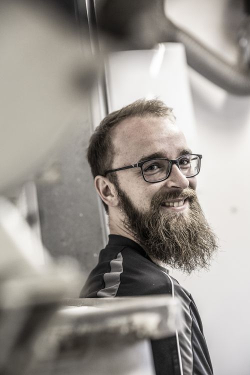 Ein lächelnder Haustechniker in München arbeitet an moderner Heiztechnik im Gebäude.