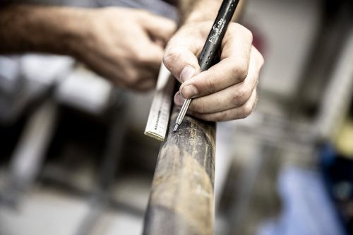 Ein Handwerker markiert präzise Maße auf einem Rohr für die Heiztechnik mit einem Stift.