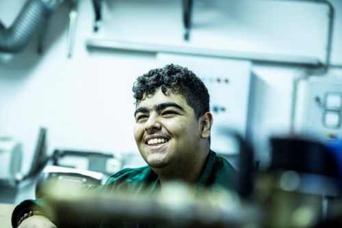 Ein lächelnder Mitarbeiter in grüner Arbeitskleidung arbeitet gut gelaunt in der Sanitärabteilung.