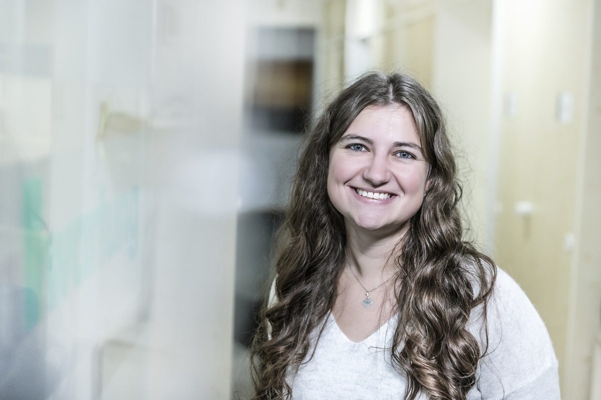 Eine lächelnde Frau steht in einem hellen Flur und repräsentiert modernen Service in der Klimatechnik.