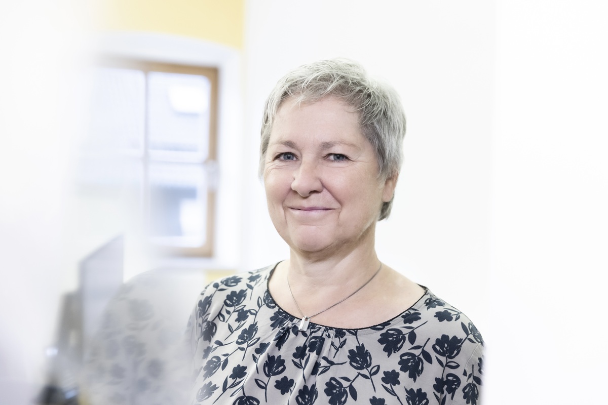 Eine lächelnde Frau in einem Büro, umgeben von sanitärem Equipment und modernem Heiztechnik-Design.